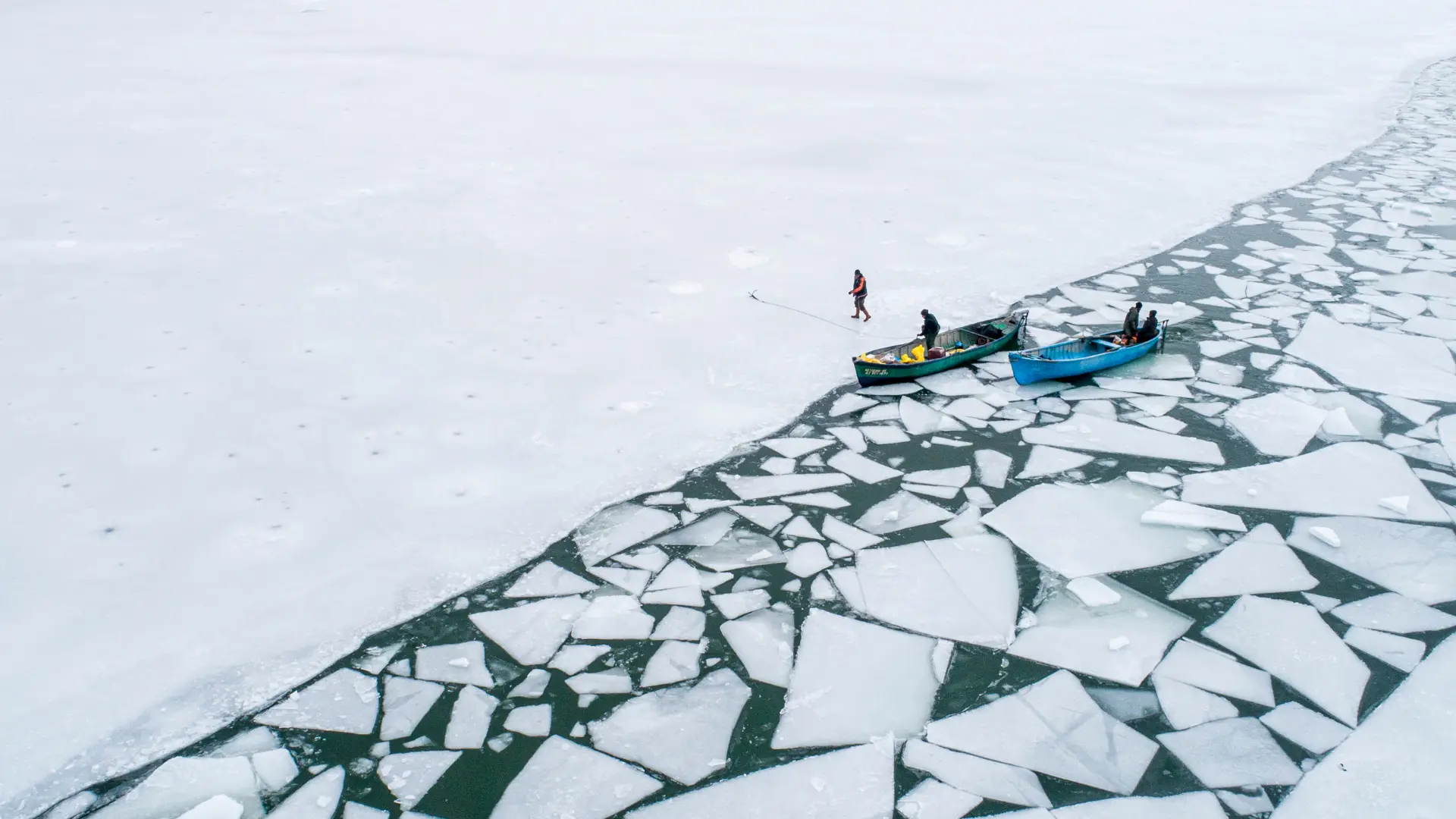 Fishing boats at the edge of sea ice breaking into floes